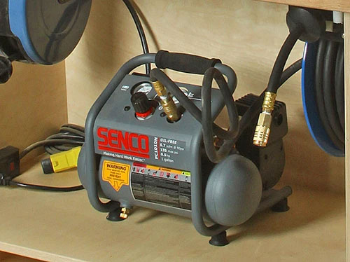 Portable air compressor underneath a workshop bench