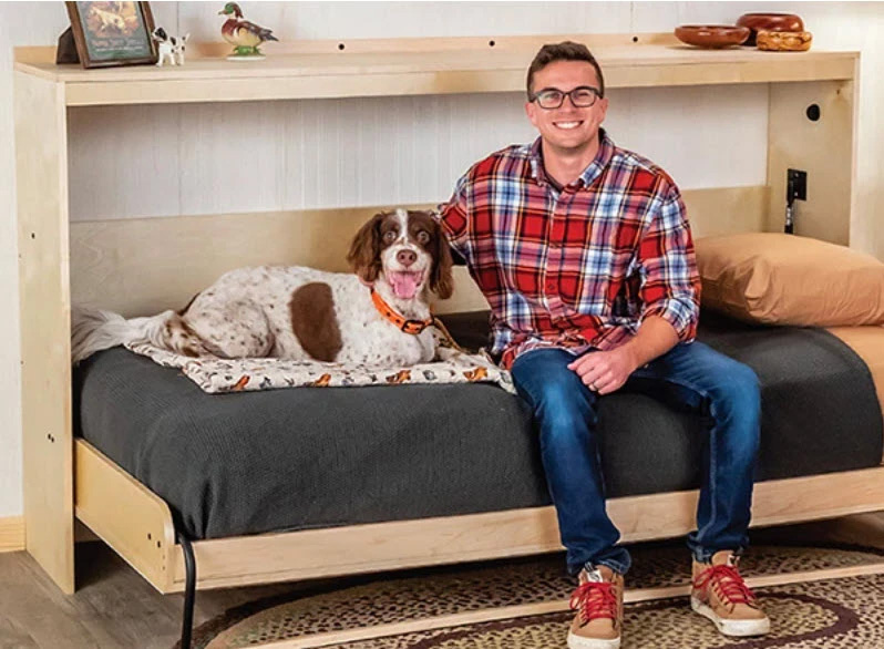 Man and dog sitting on fold-down murphy bed