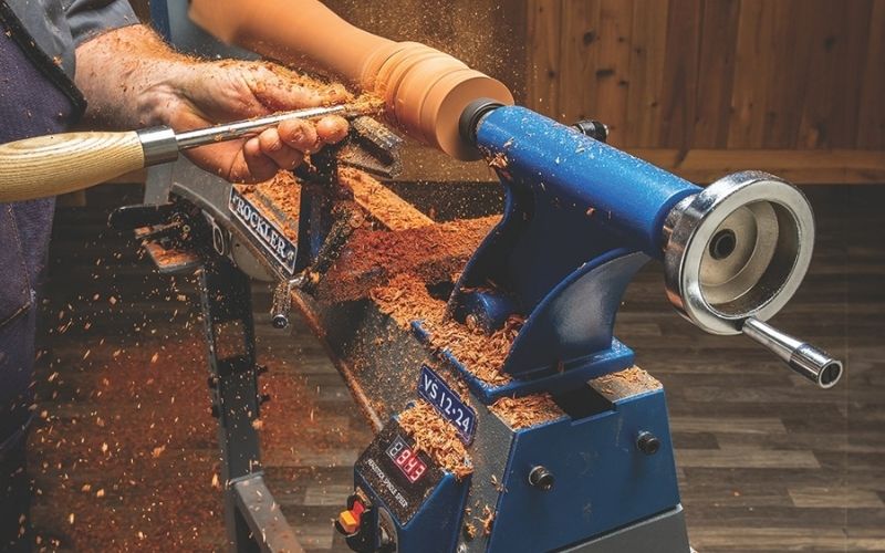 man turning on benchtop lathe