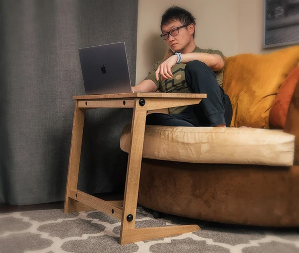 Man sitting on sofa with computer on sofa table
