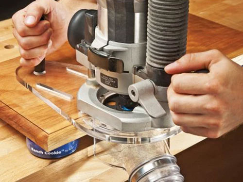 Router cutting the edge of the board with a dust shield equipped