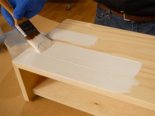 Brushing a coat of paint onto woodworking project