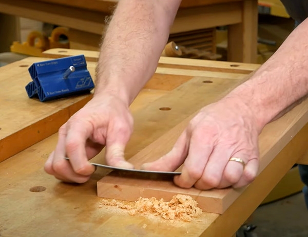 cabinet scraper smoothing a board