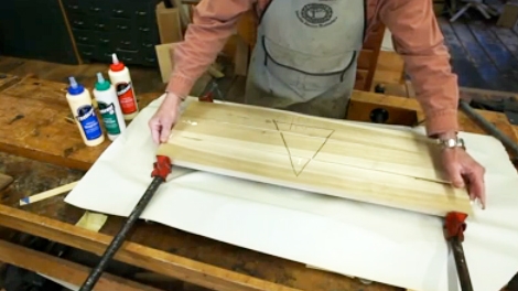 Using bar clamps to glue wood pieces into a panel
