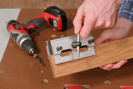 Engaging the clamp on a doweling jig attached to a board