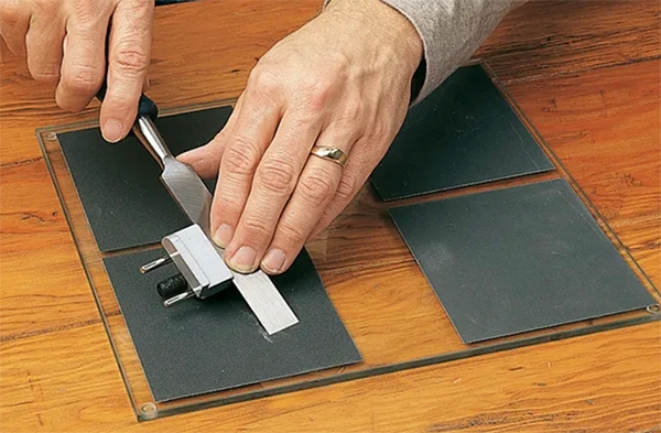 sharpening a chisel on sandpaper and a glass plate
