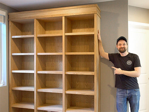 Michael Alm standing with his large display case bookshelf