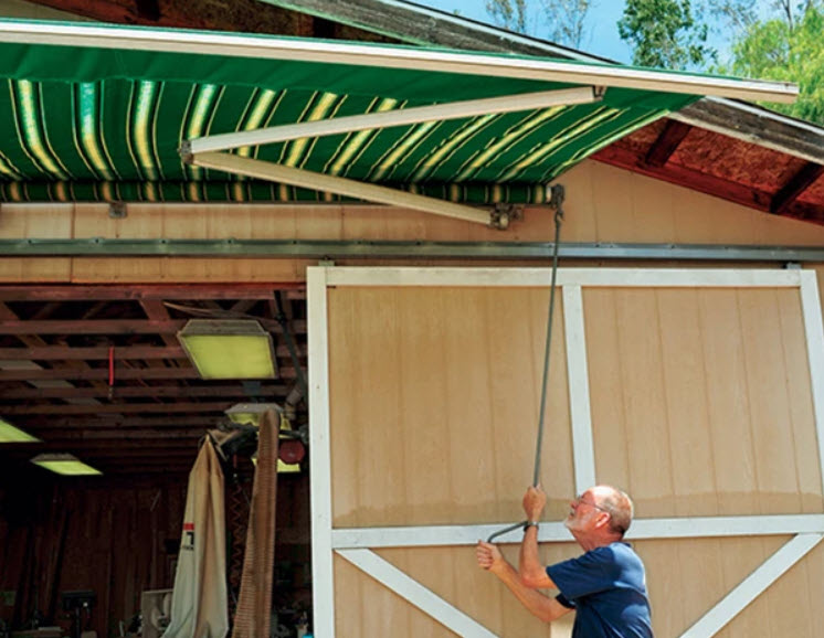 man putting up awning on garage workshop