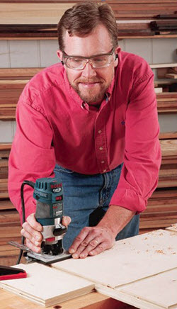 man using trim router to cut joinery