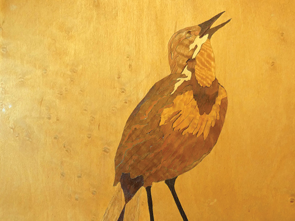 Image of a bird created in wood with marquetry inlays