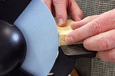 Checking the distance between tool rest and grinding wheel with scrap wood