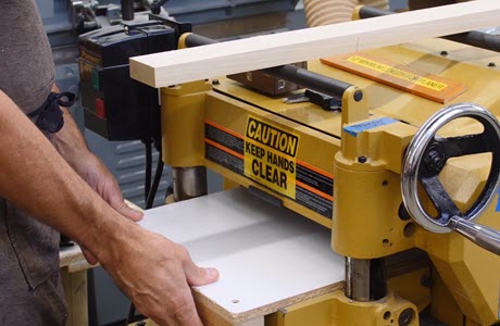 man putting wood through planer
