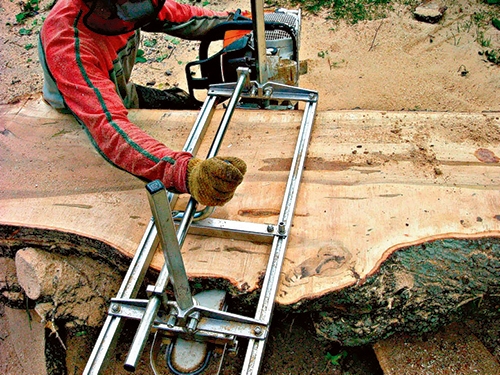 Chainsaw attached to rail making plank cuts