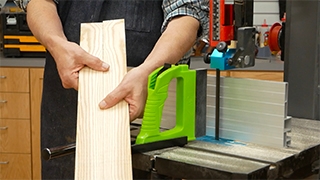 man holding two matching boards next to a band saw