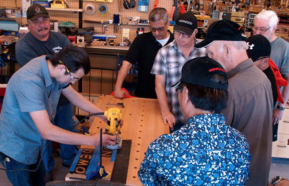 group of people watching a demonstration of a handheld router
