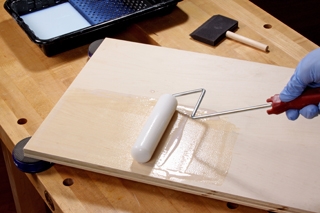 Using a foam roller to add clear finish to a cabinet panel