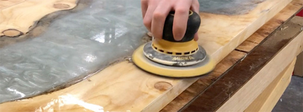 Using a random orbit sander to sand epoxy table surface
