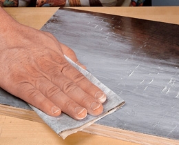 Sanding across wood treated with wood sealer