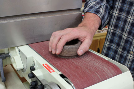 Sanding paper residue off of glue block with a belt sander