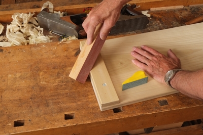 Using a piece of scrap wood to guide sanding