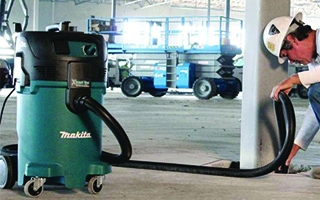 man using power tool showing dust hose attached to capture sawdust