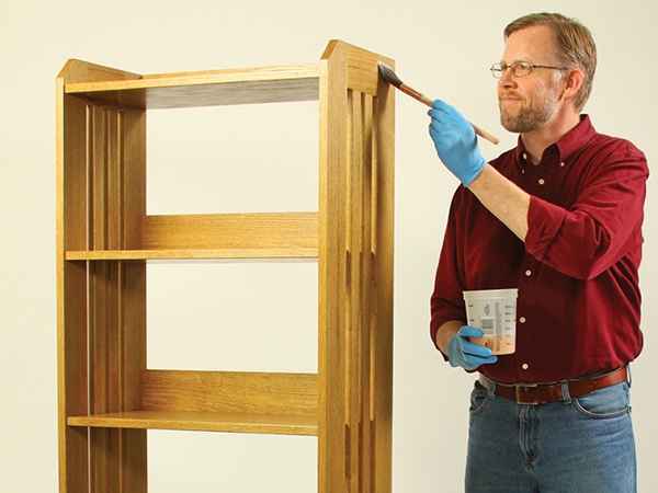 Applying stain to a bookshelf