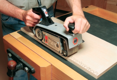Using a belt sander to sand edging flush with base