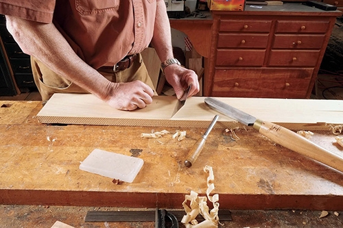 Using a card scraper to shave a board