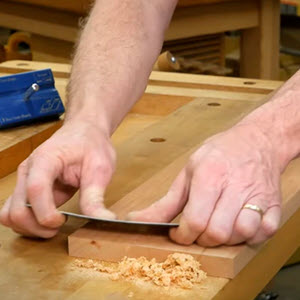 cabinet scraper being used to scrape wood
