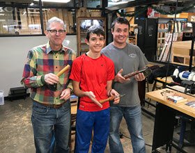Three guys showing off their completed projects from a handle turning class