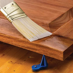 paint brush applying finish to cabinet door